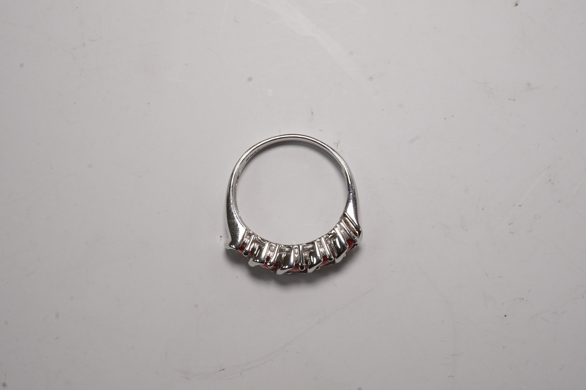 A modern 18ct white gold and five stone orange/pink stone set half hoop ring, size M/N, gross weight 5.6 grams. Condition - fair to good